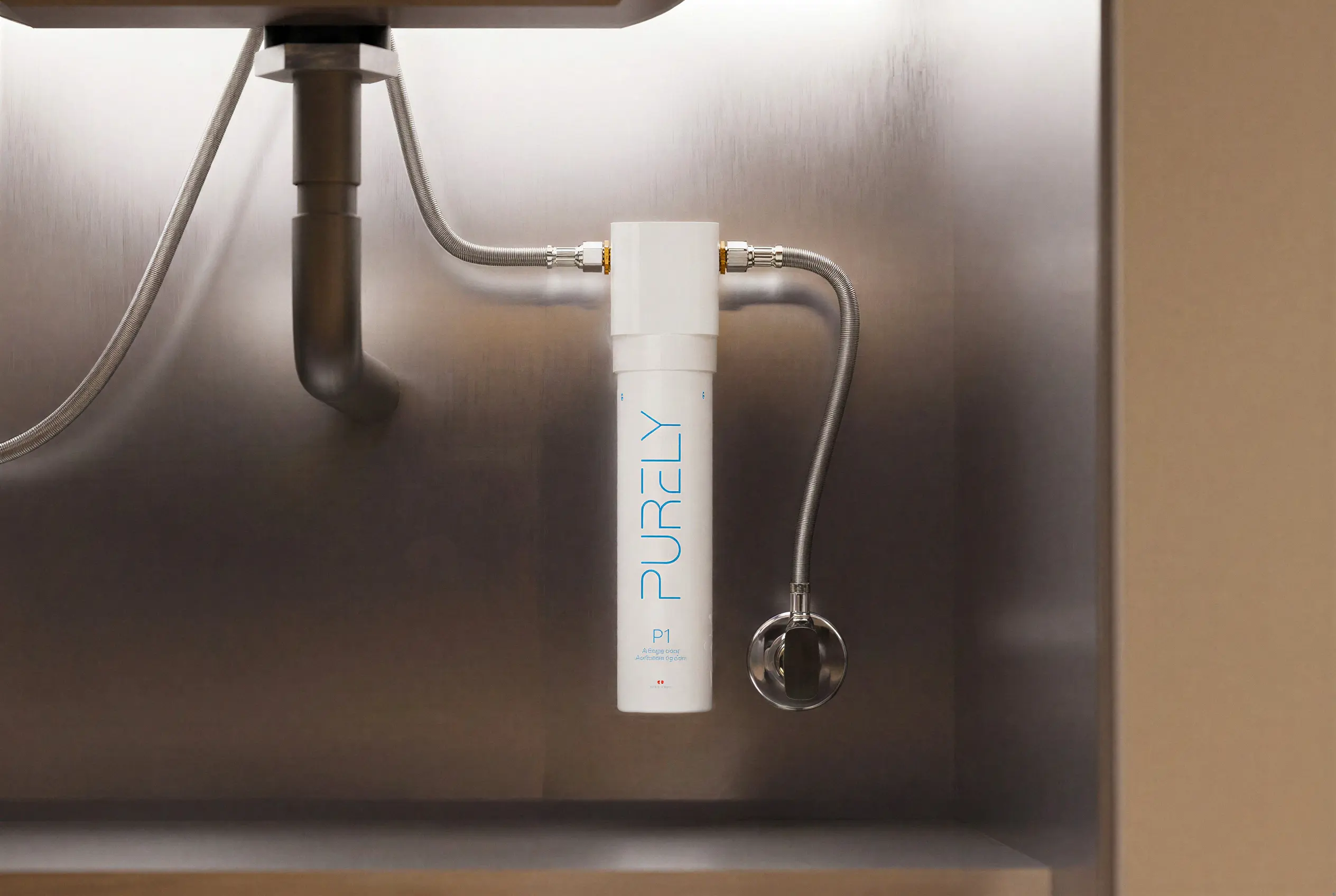 The Purely P1 under-sink filter installed on a stainless braided water line beneath a sink